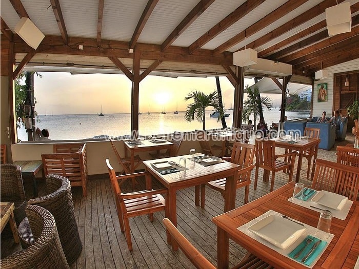 Salle de restaurant ouverte sur un coucher de soleil en Martinique